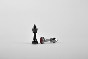 two chess pieces one standing up the other fallen over